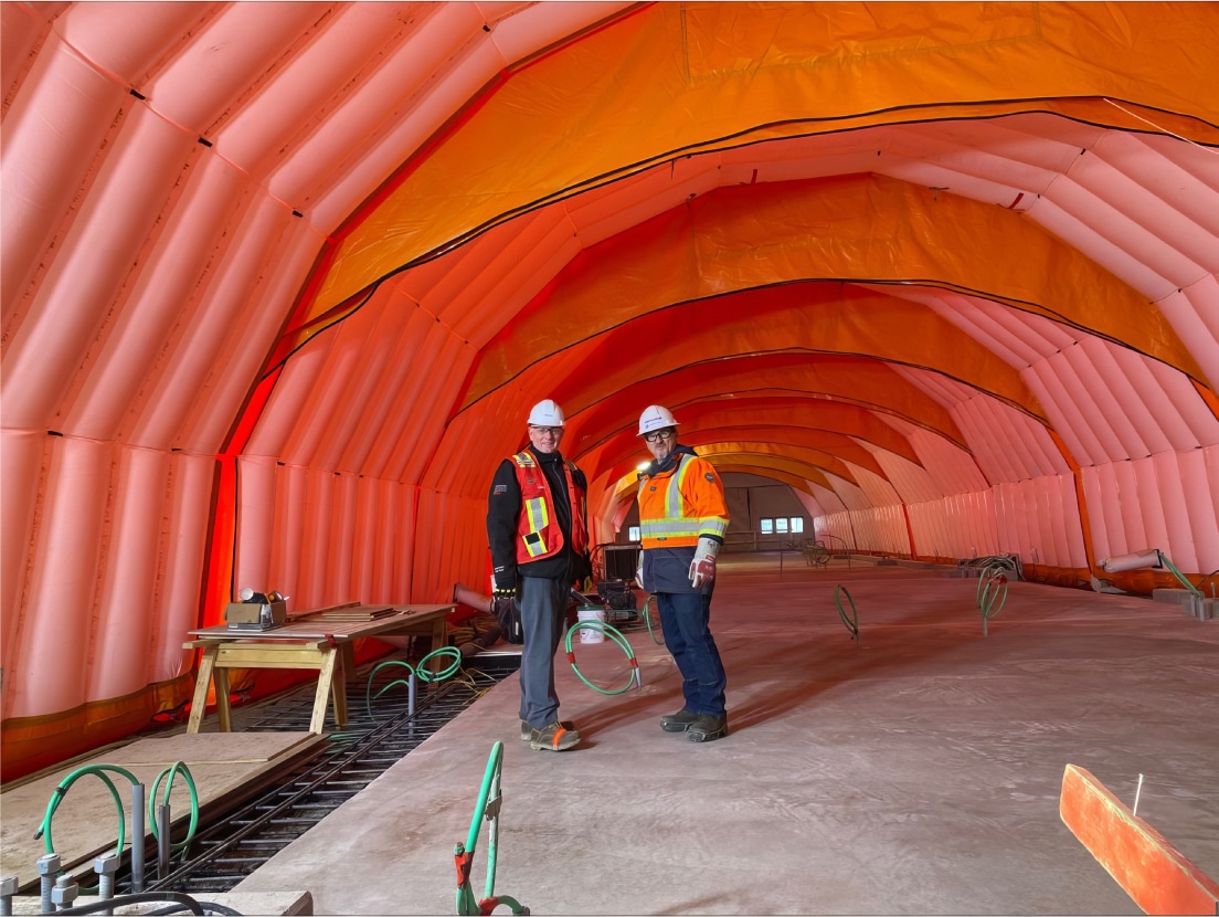 Two construction workers standing inside a Fast Tent