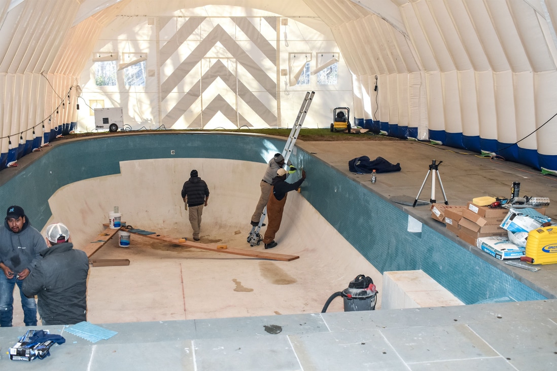 Pool construction guys working inside an inflatable construction tent